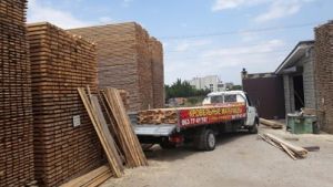 Грузовик компании Современная кровля на складе леса Выгрузка леса для кровли